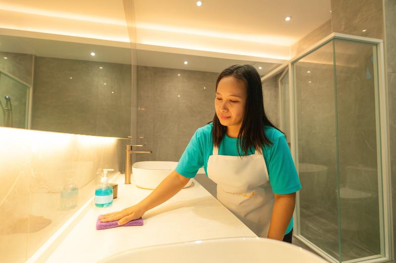 Professional maid wiping bathroom counter and maintaining cleanliness in a Malaysian home, part of Top Quick Maid Agency’s trained helper service.